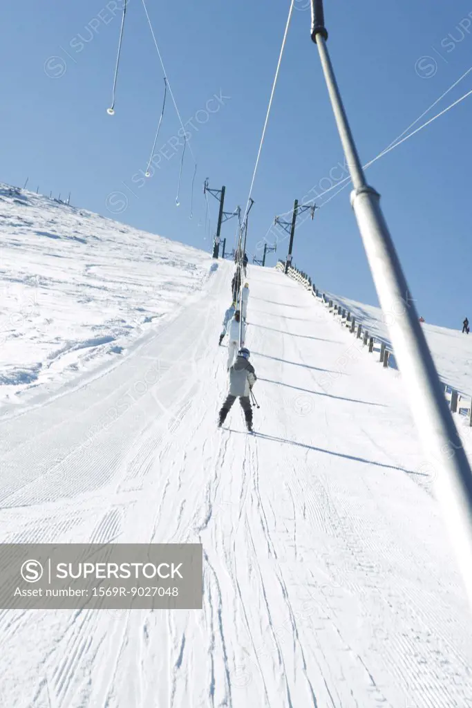 Young skiers using ski lift on ski slope, low angle view