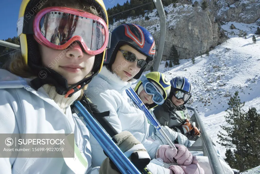 Young skiers on chair lift, smiling at camera