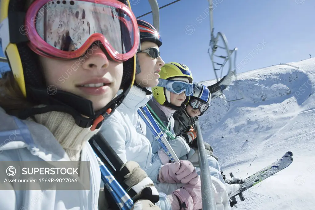 Four young skiers on chair lift, two looking at camera
