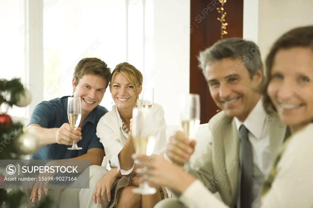 Adult friends making a toast with champagne, smiling at camera