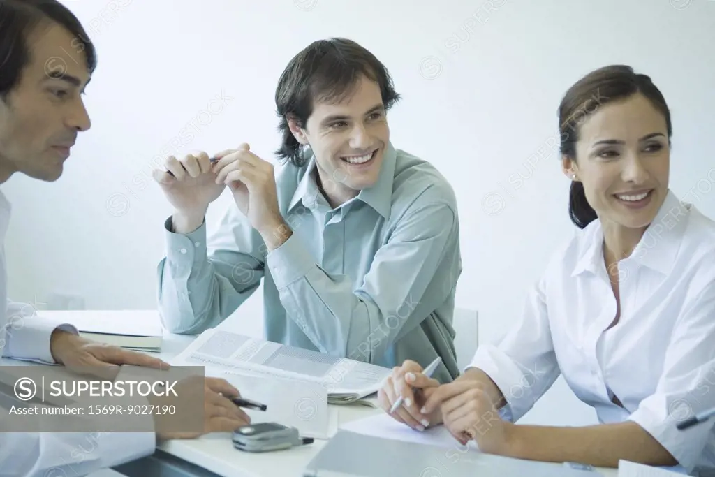 Business associates seated at table, chatting, smiling