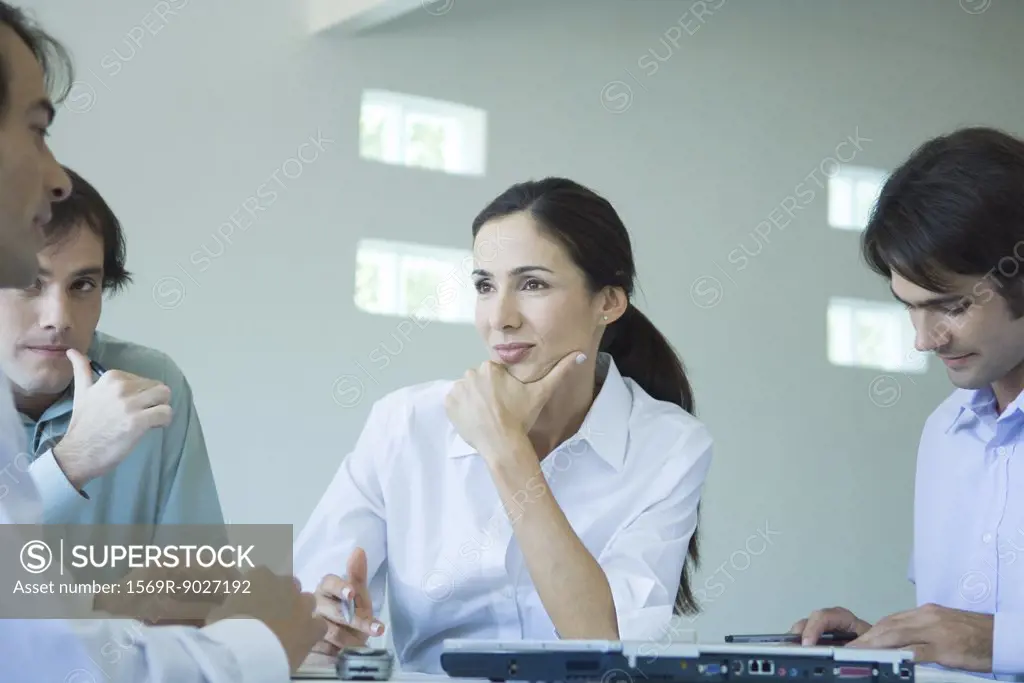 Business associates having casual meeting, focus on woman holding chin, listening to colleague