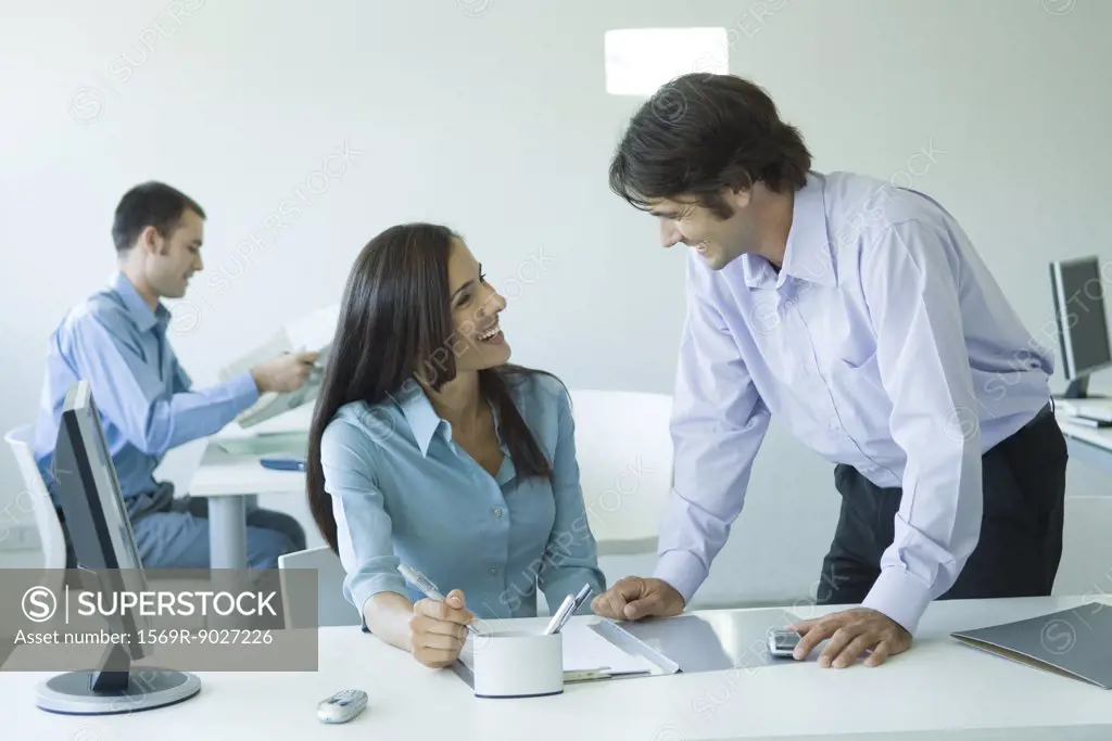 Businesswoman and male colleague laughing together in office