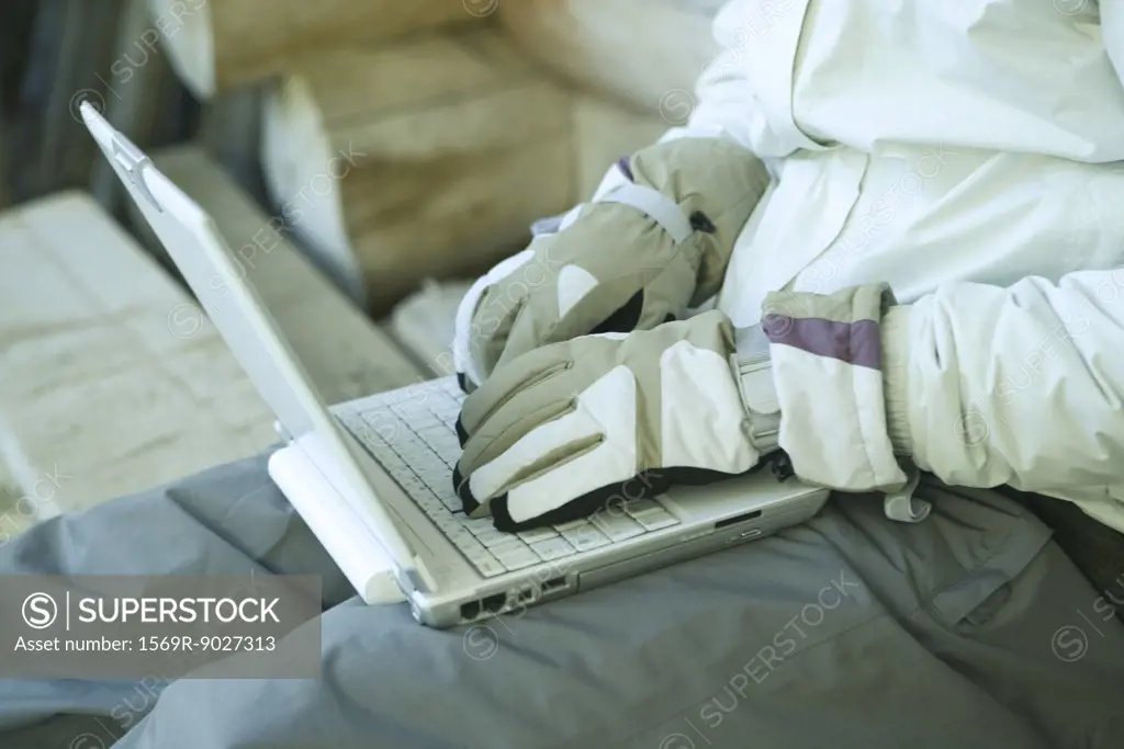 Man using laptop with gloves on