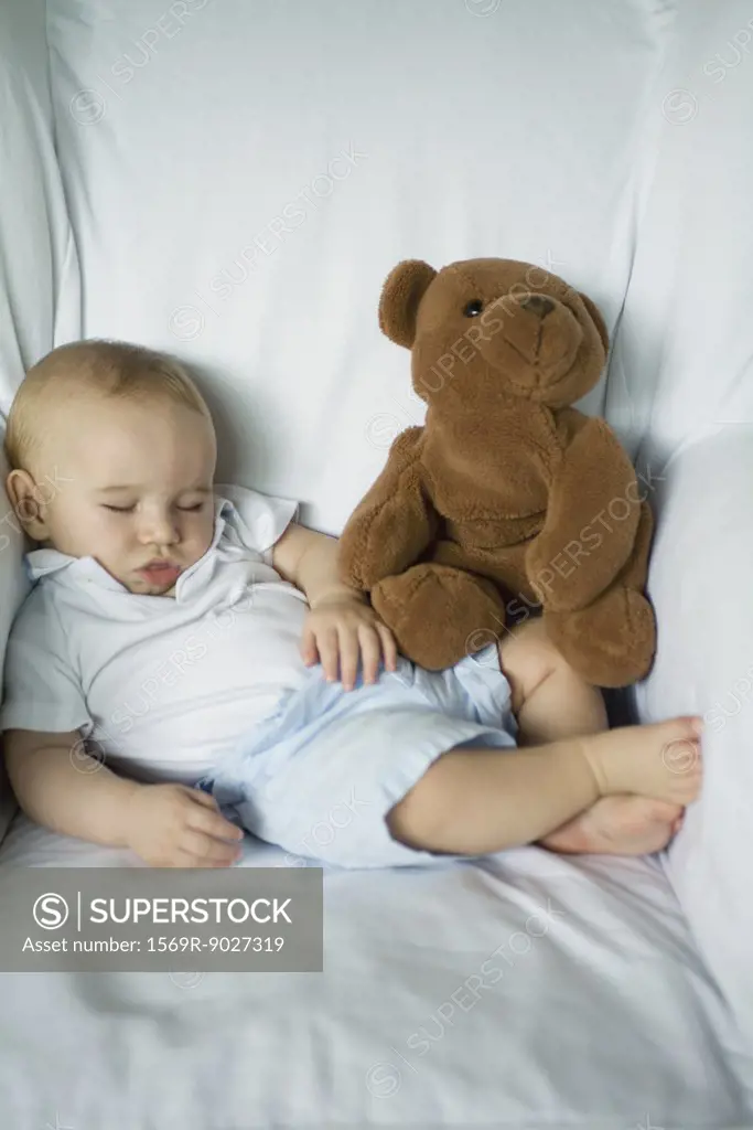 Baby sleeping in arm chair with teddy bear, portrait