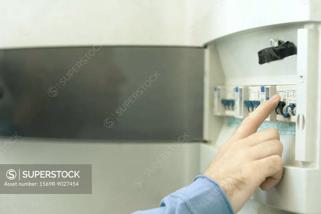 Man switching fuse in fuse box, close-up of hand