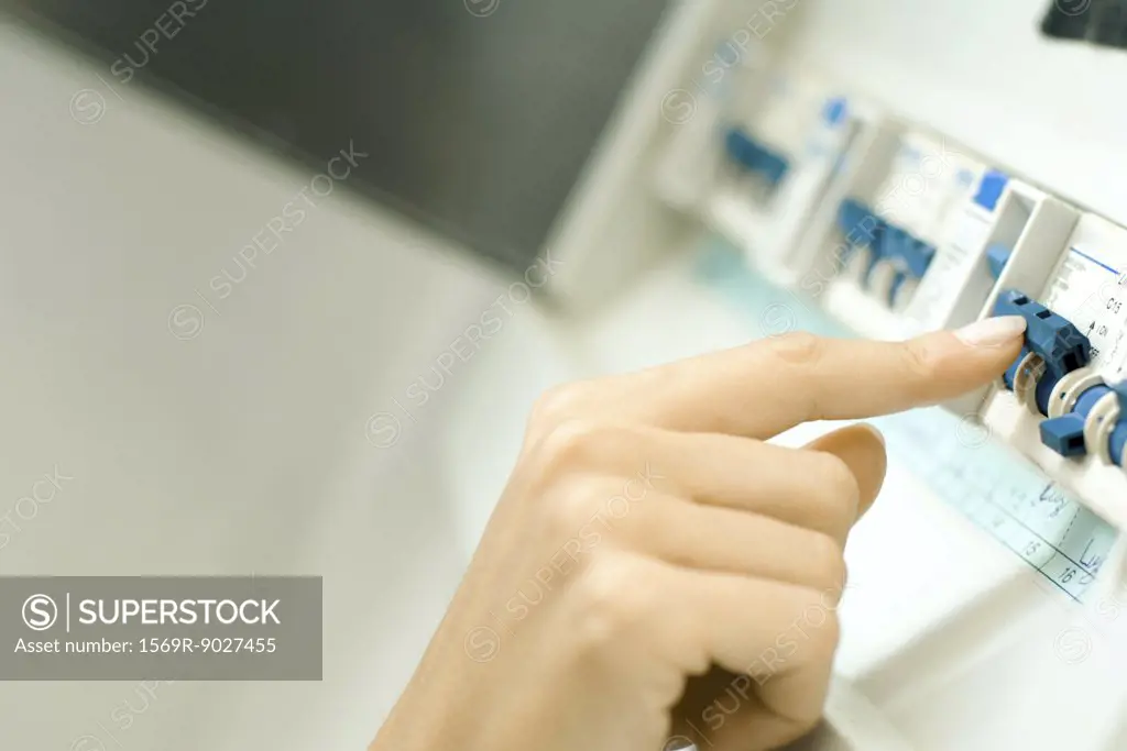 Woman switching fuse in fuse box, close-up of hand