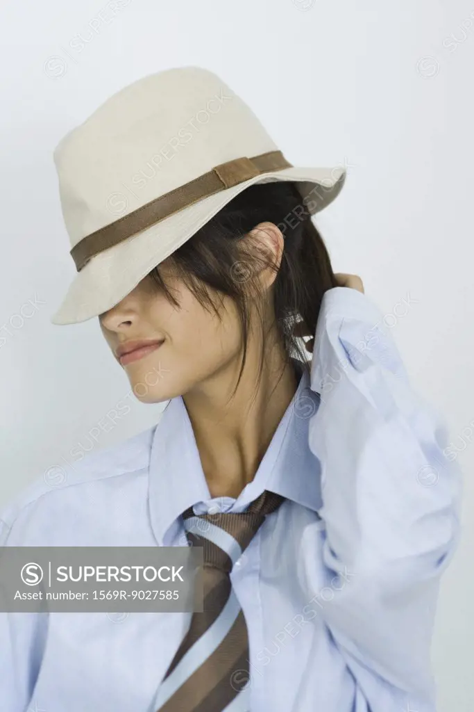 Teenage girl wearing hat and tie, eyes covered, portrait