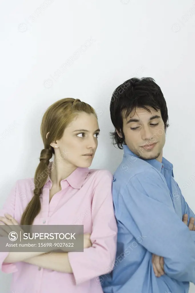 Young couple looking at each other over their shoulders, arms folded