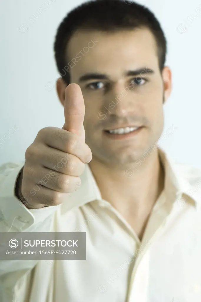 Man looking at camera, giving thumbs up sign, portrait