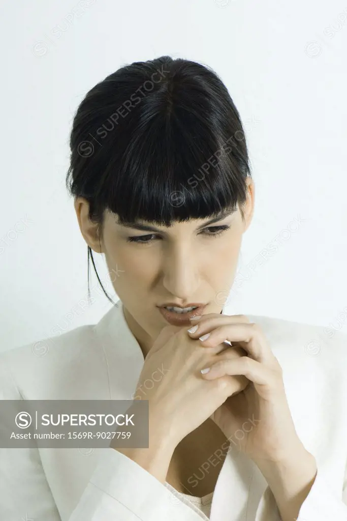 Young businesswoman, holding hands under chin, looking down, portrait