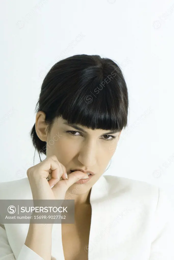 Well-dressed young businesswoman biting thumb, looking at camera, portrait