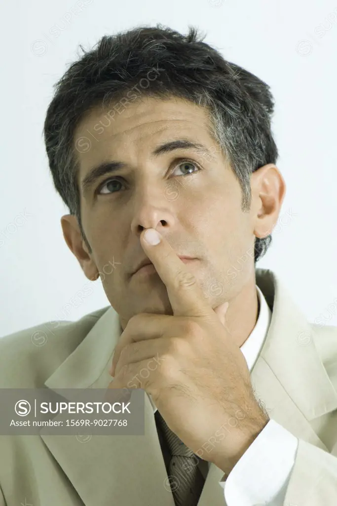 Businessman holding finger over lips, looking up