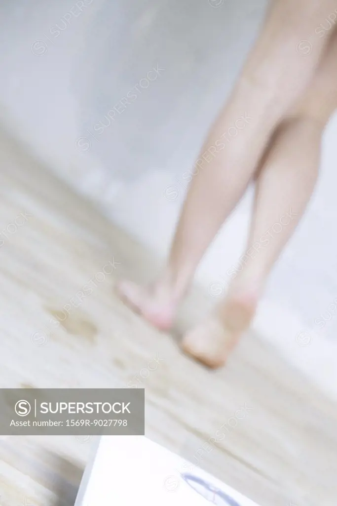 Woman walking away from bathroom scale, low section, cropped view