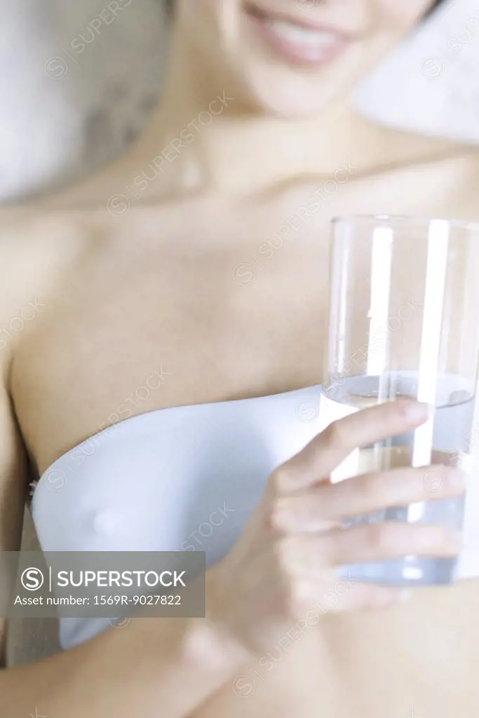 Cropped view of woman holding glass of water, dressed in tubetop