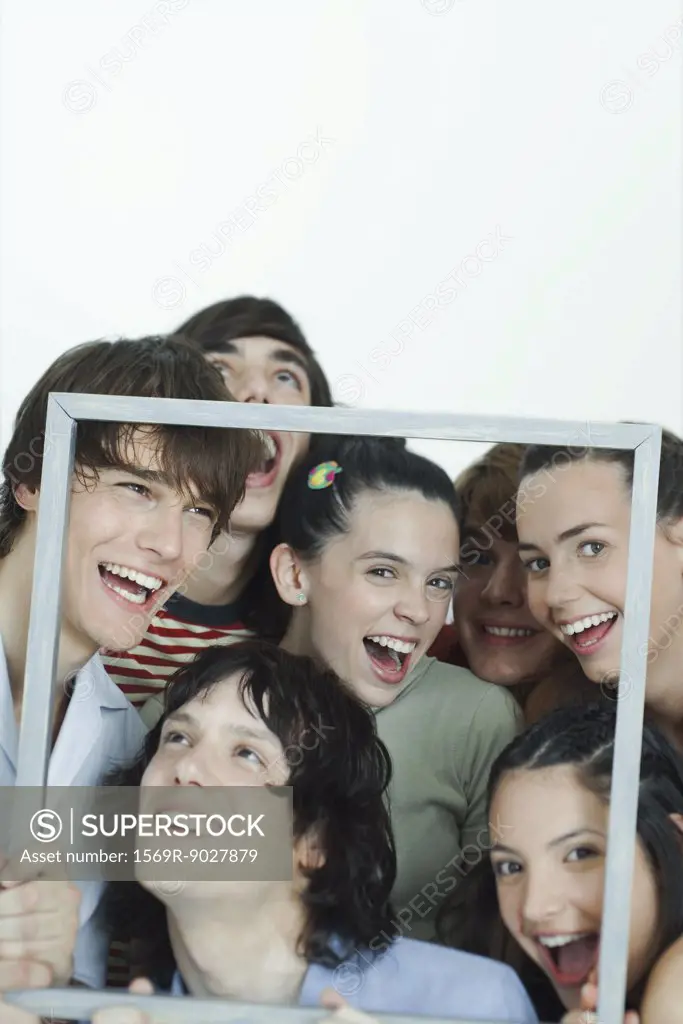 Group of young friends posing for photo, holding up picture frame, laughing, portrait