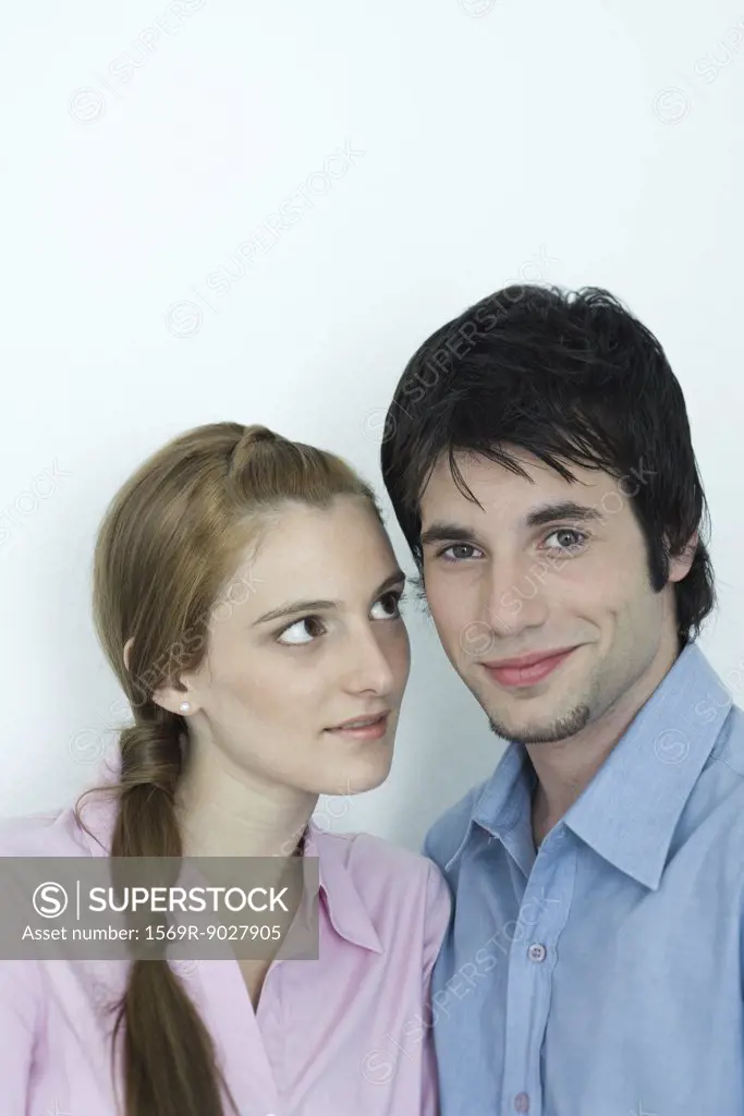 Young couple, man smiling at camera, woman looking at man with admiration, portrait