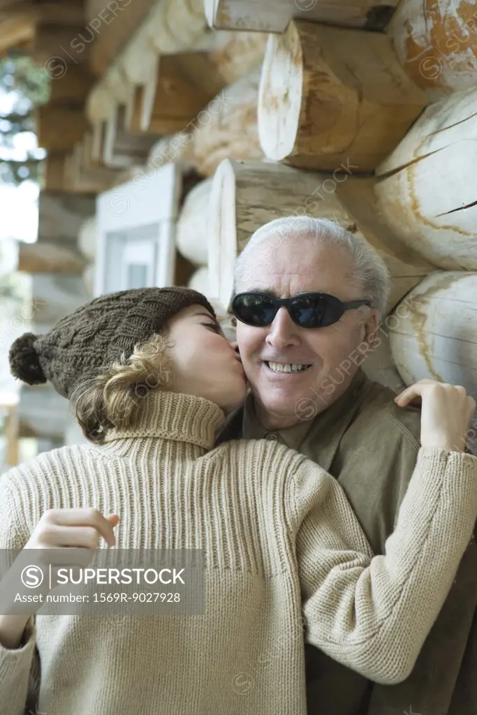 Teenage girl kissing grandfather on the cheek, portrait