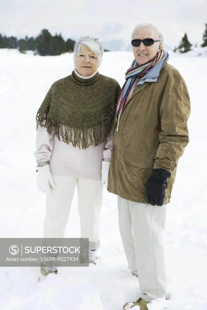 Senior couple standing side by side outdoors, looking at camera, portrait