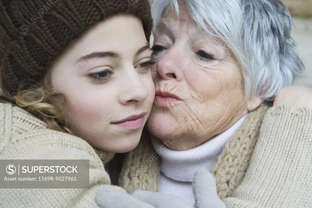 Grandmother kissing teenage girl on the cheek, portrait