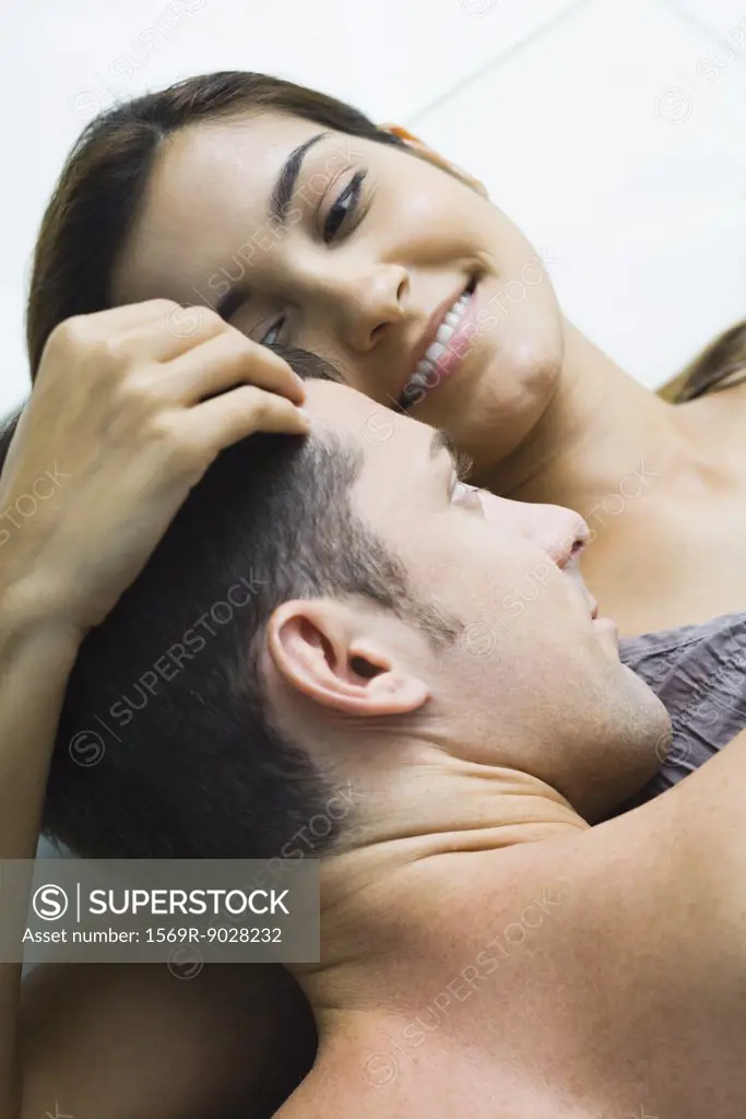 Man lying on top of woman, woman holding his head, smiling, high angle view