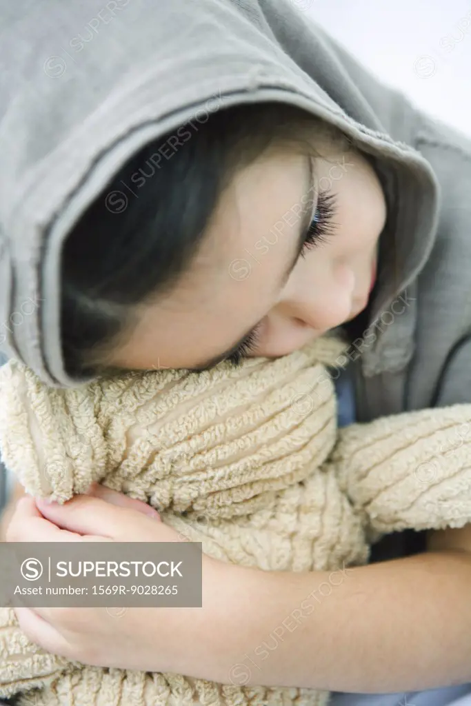 Little girl resting head on teddy bear, close-up