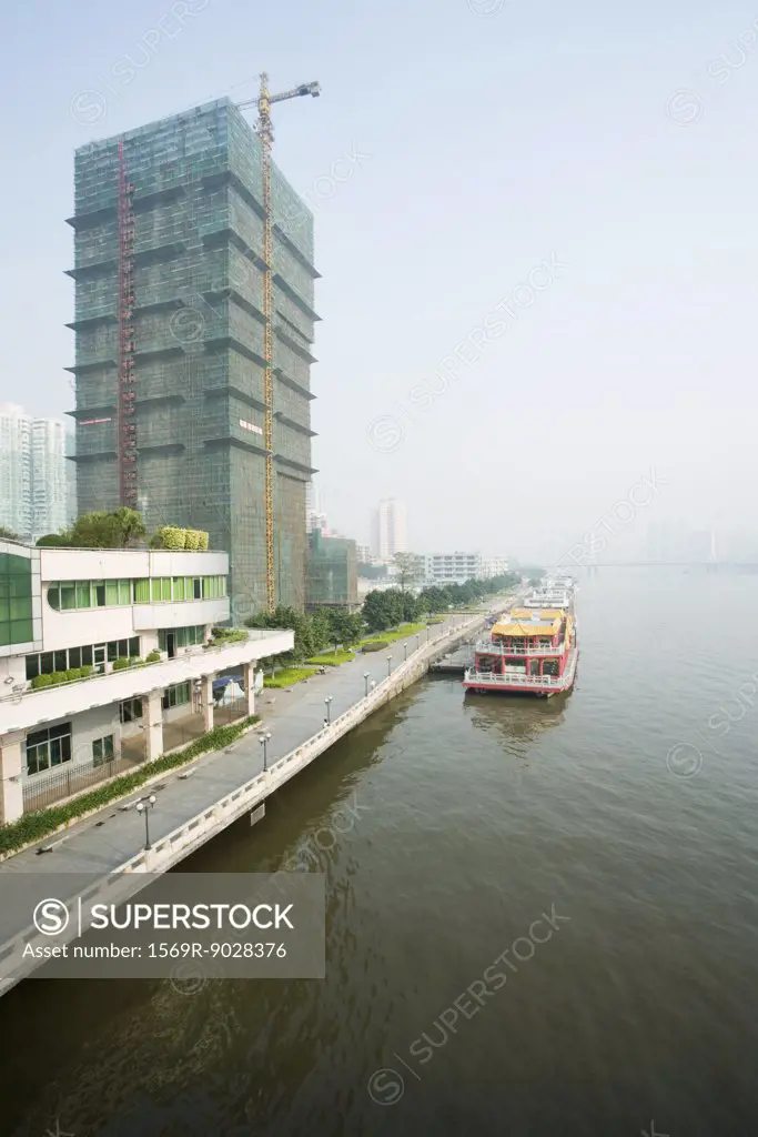 China, Guangdong Province, barge parked along quay near high rise under construction