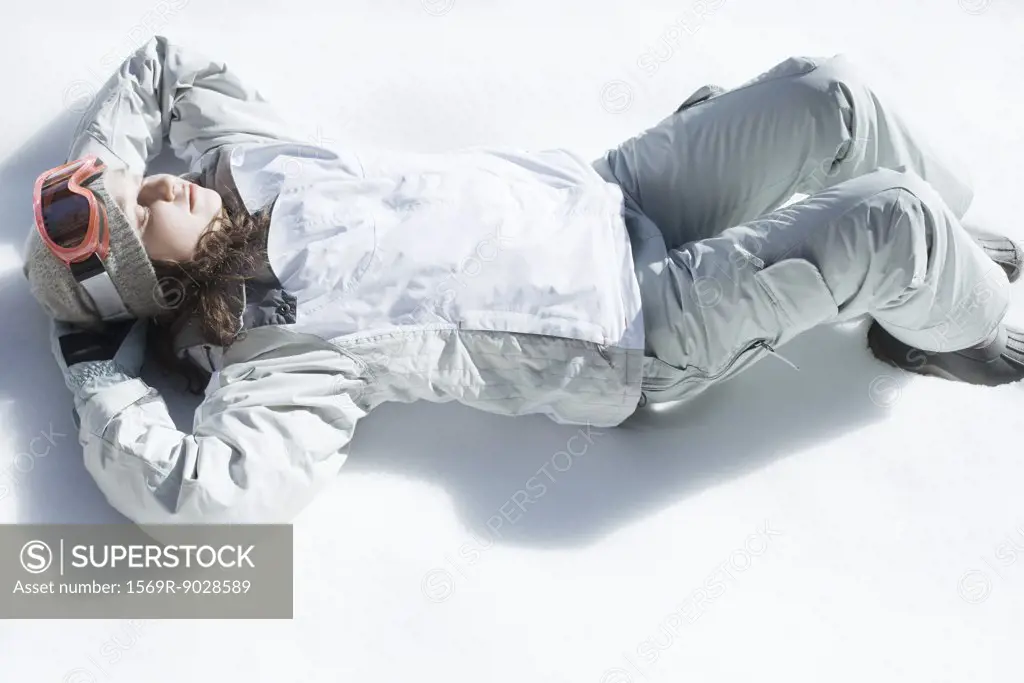 Teenage girl lying on snow, high angle view