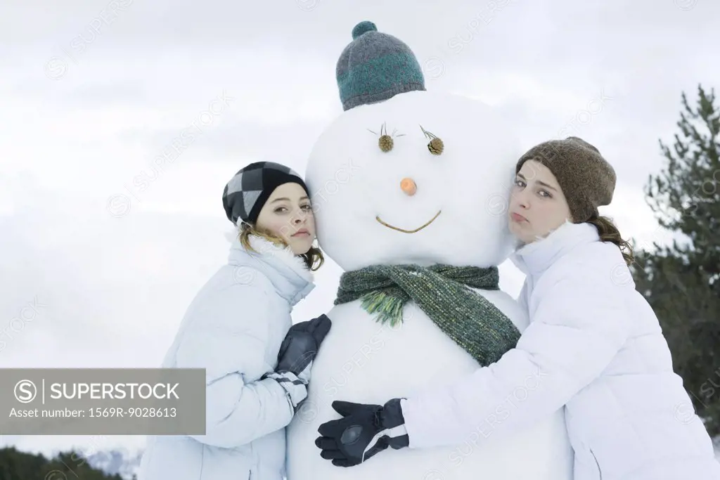 Teen girls leaning against snowman