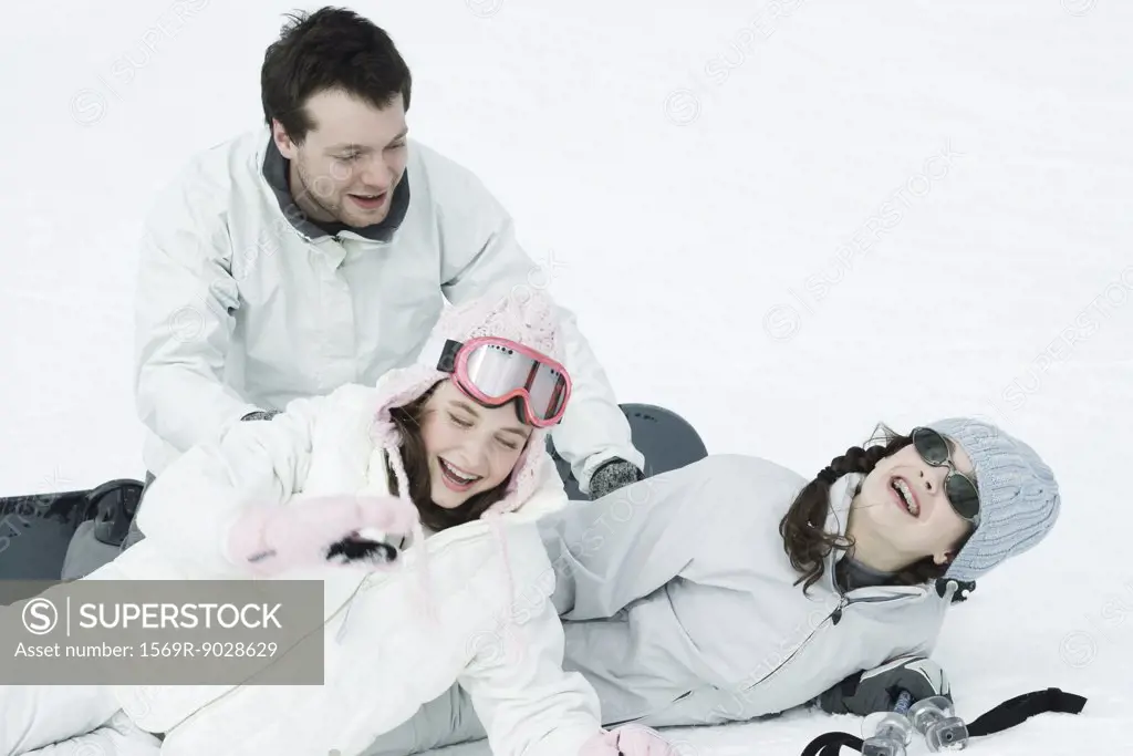 Young friends playing around in snow, laughing