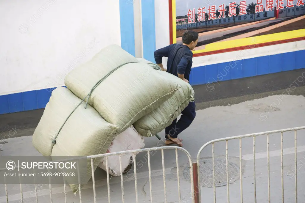 Man carting cushions through street, China, Guangdong Province, Guangzhou.