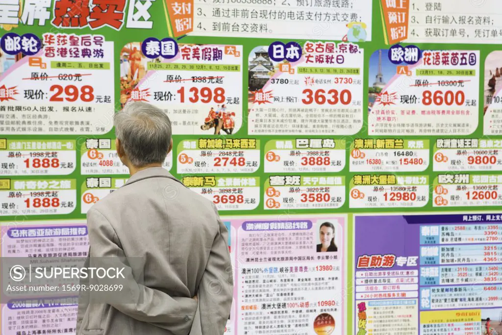 Man looking at ads on wall in Chinese, rear view
