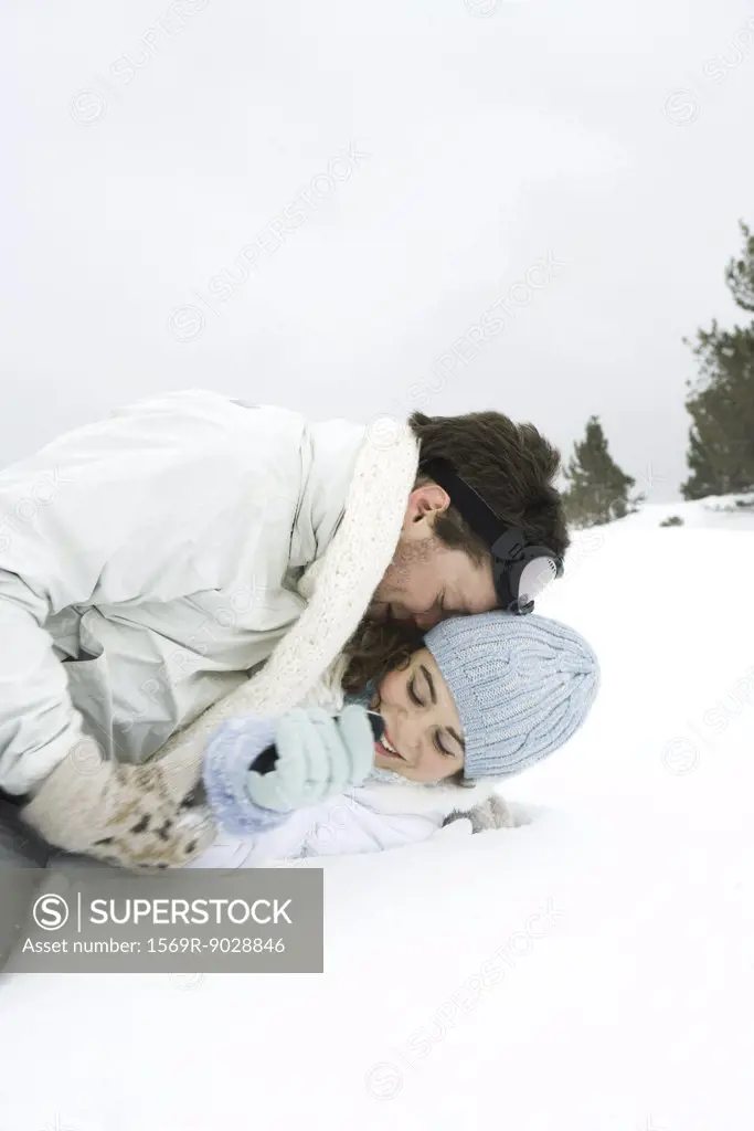 Young couple reclining in the snow, playing around