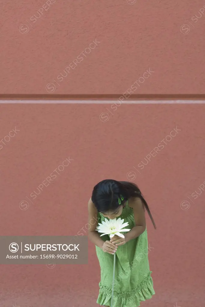 Girl standing, bending over, smelling flower