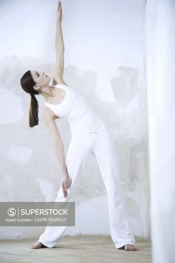 Woman standing, doing yoga pose, full length