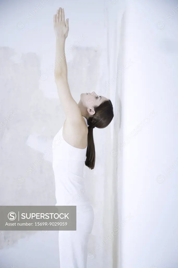 Woman standing, stretching, arms raised, head back