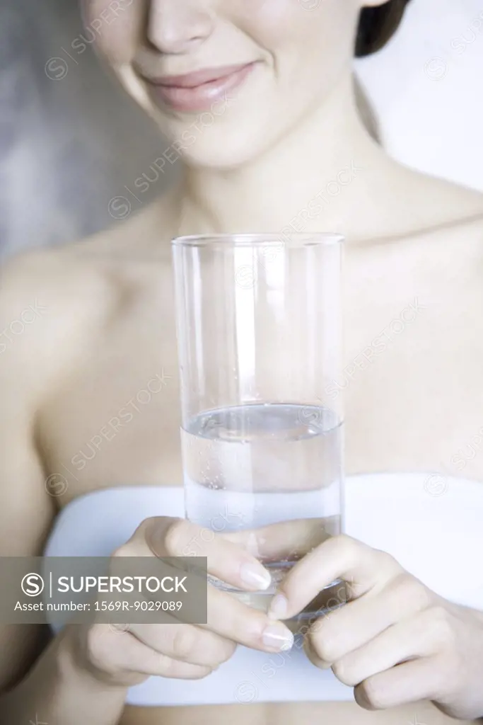 Cropped view of woman holding glass of water, smiling