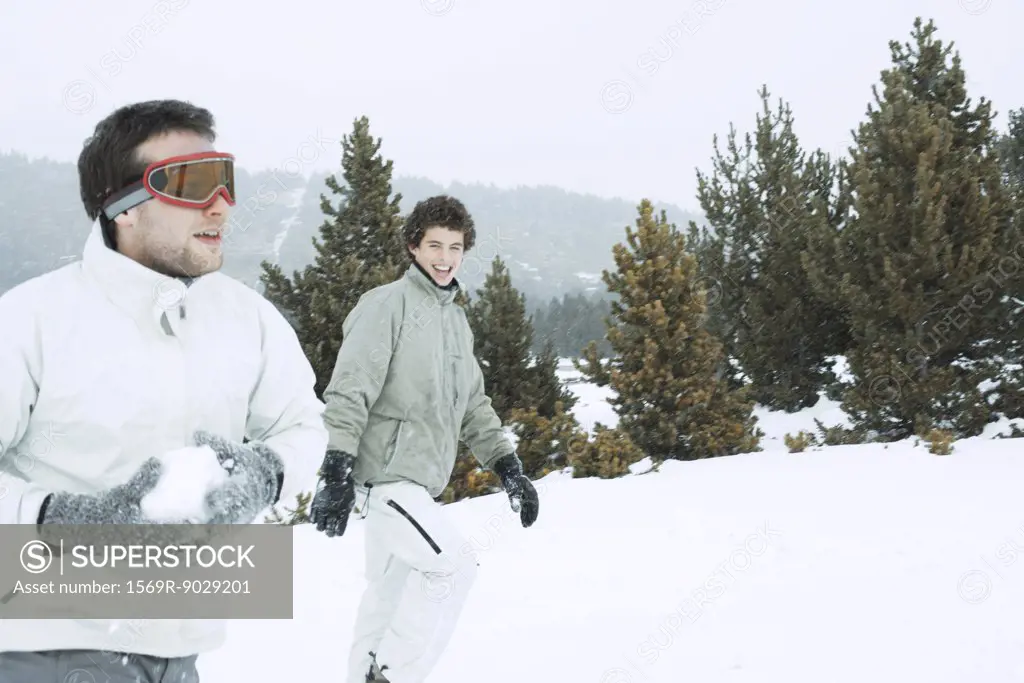 Young male friends in the snow, one holding a snowball
