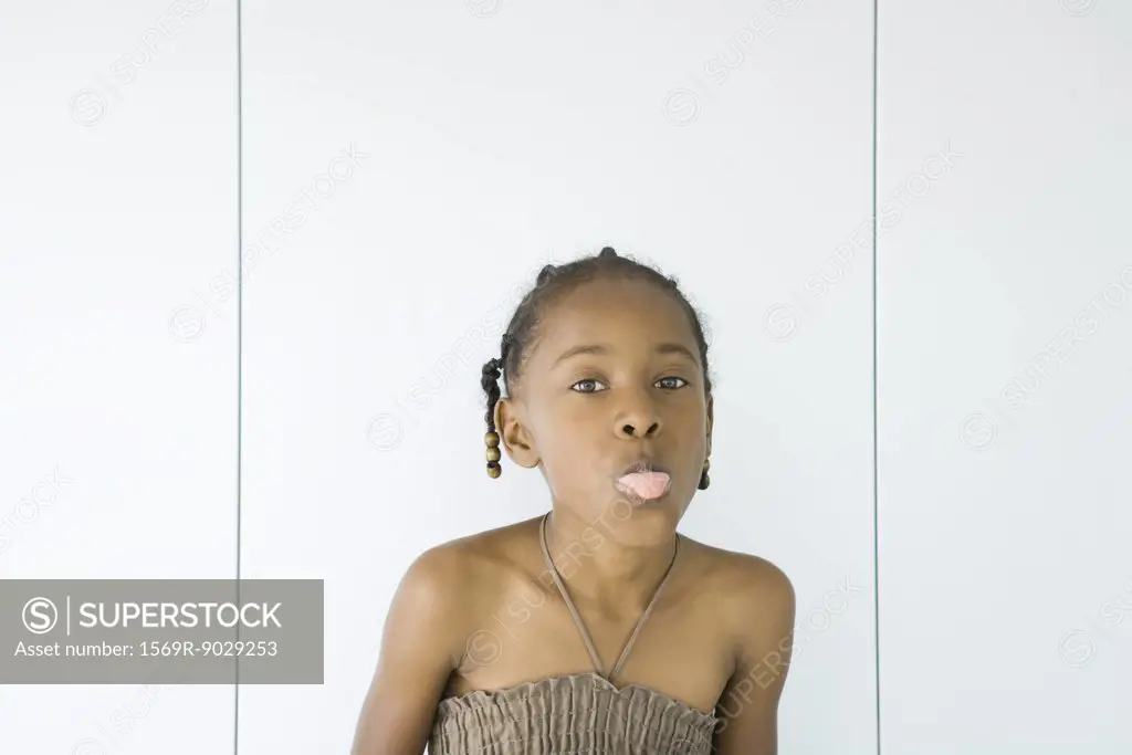 Little girl wearing halter top, sticking out tongue at camera, portrait