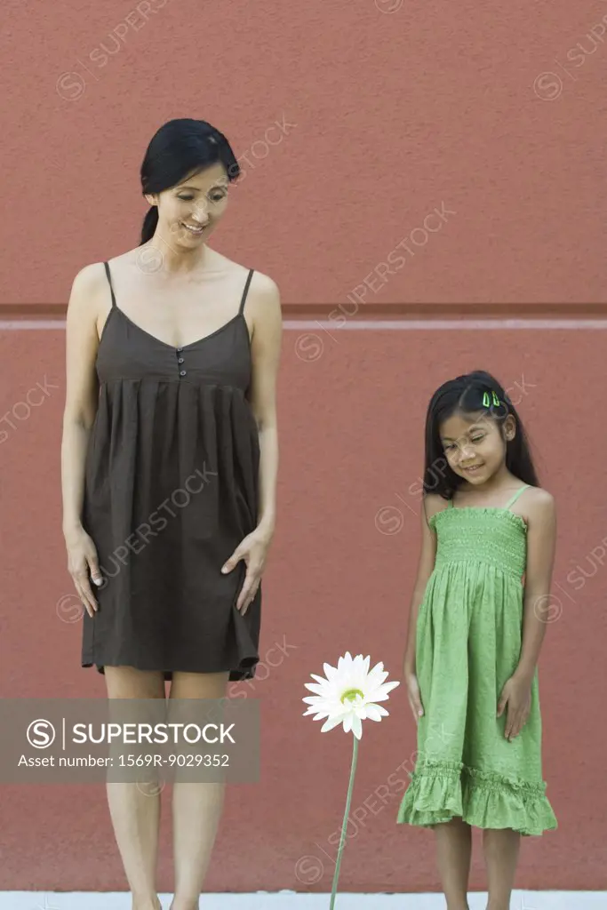 Girl and woman looking down at tall flower