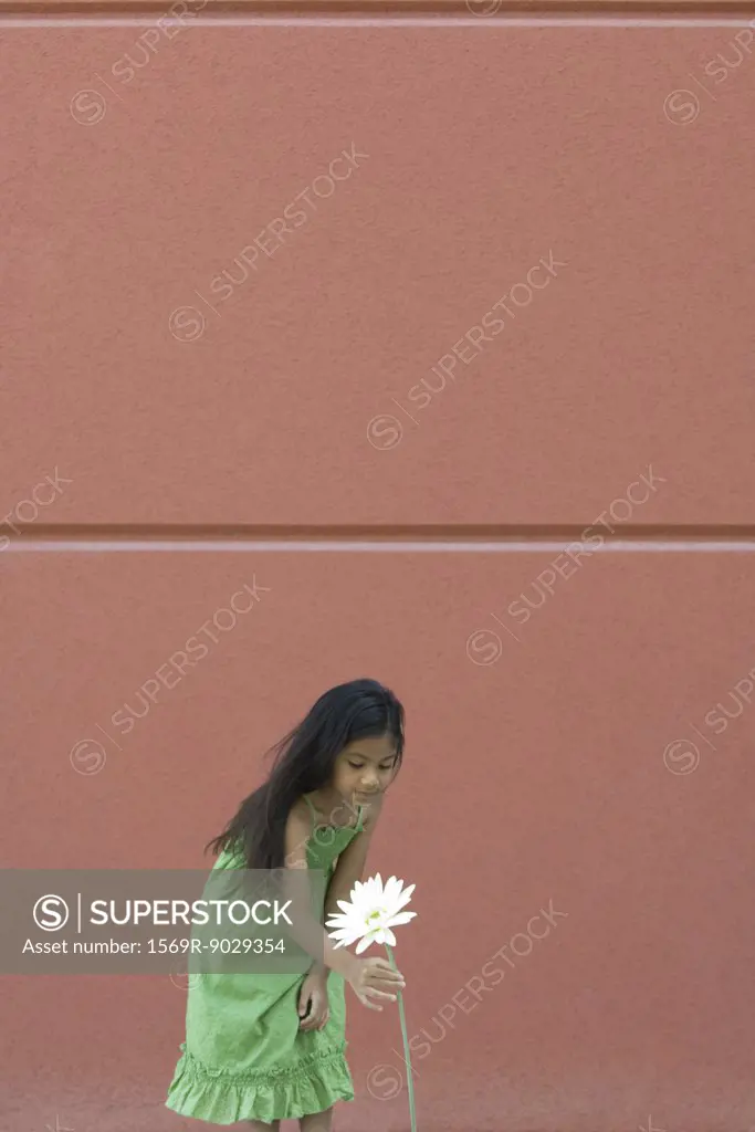 Girl bending over to pick tall flower
