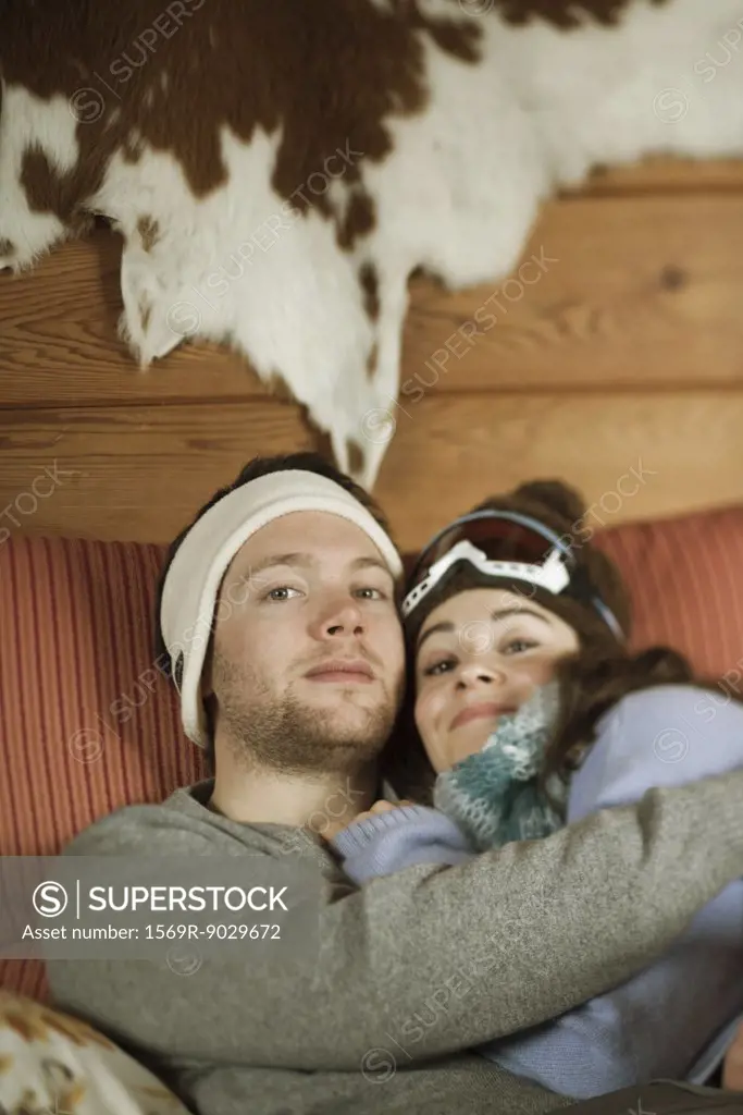 Young couple reclining on couch, smiling at camera