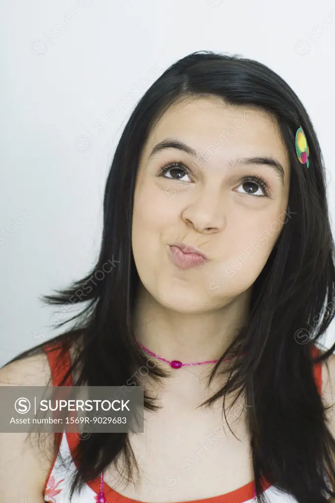 Teenage girl looking up with puffed cheeks, portrait