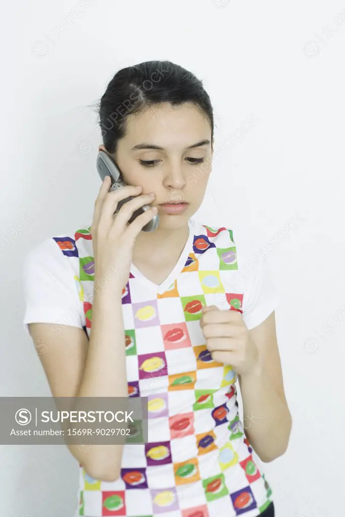 Teenage girl holding up cell phone, looking down