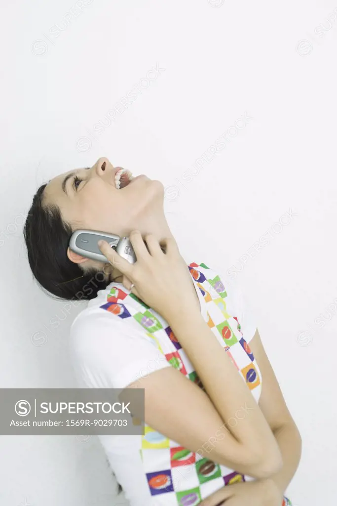 Teenage girl using cell phone, head back, laughing