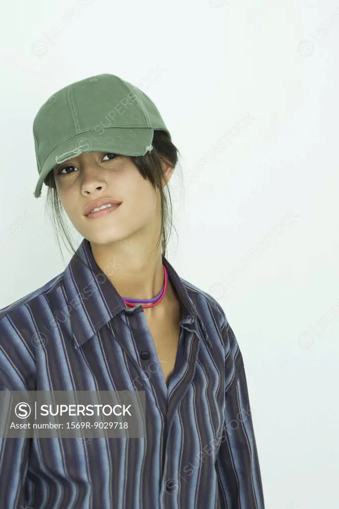 Teenage girl wearing button down shirt and cap, smiling at camera