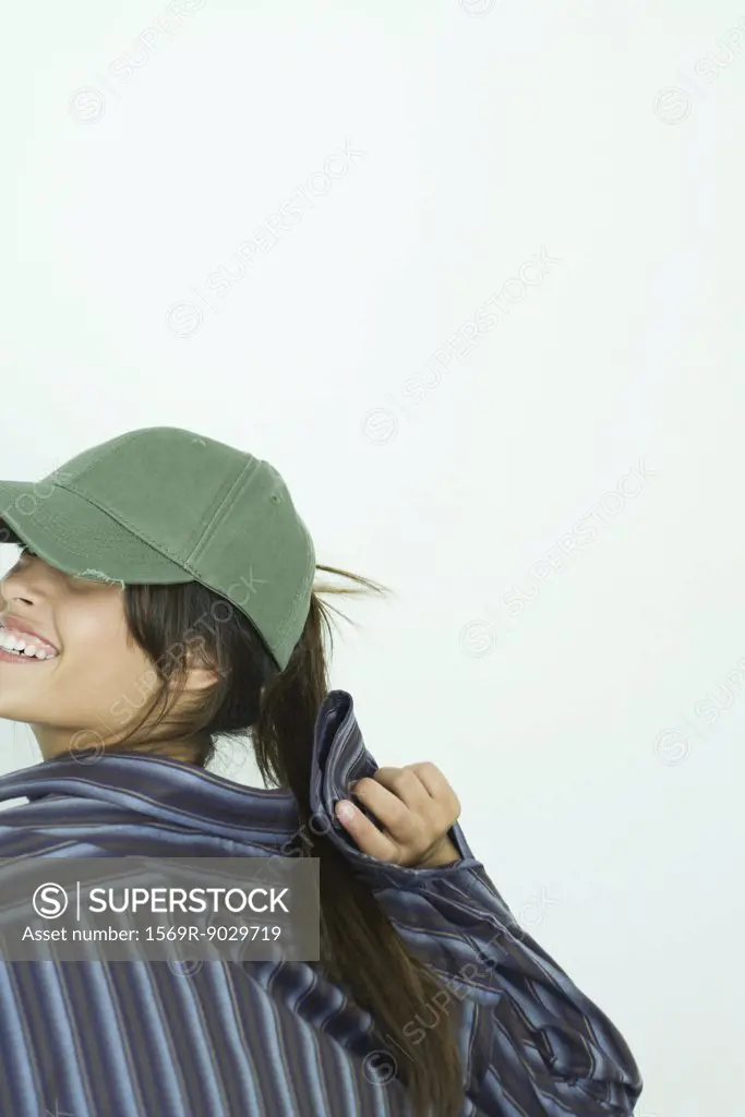 Teenage girl wearing baseball cap, looking over shoulder, cropped view