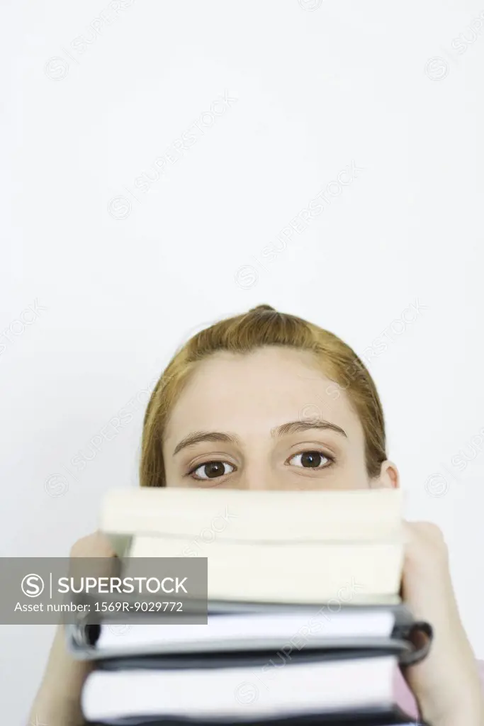 Young woman looking at camera over stack of books