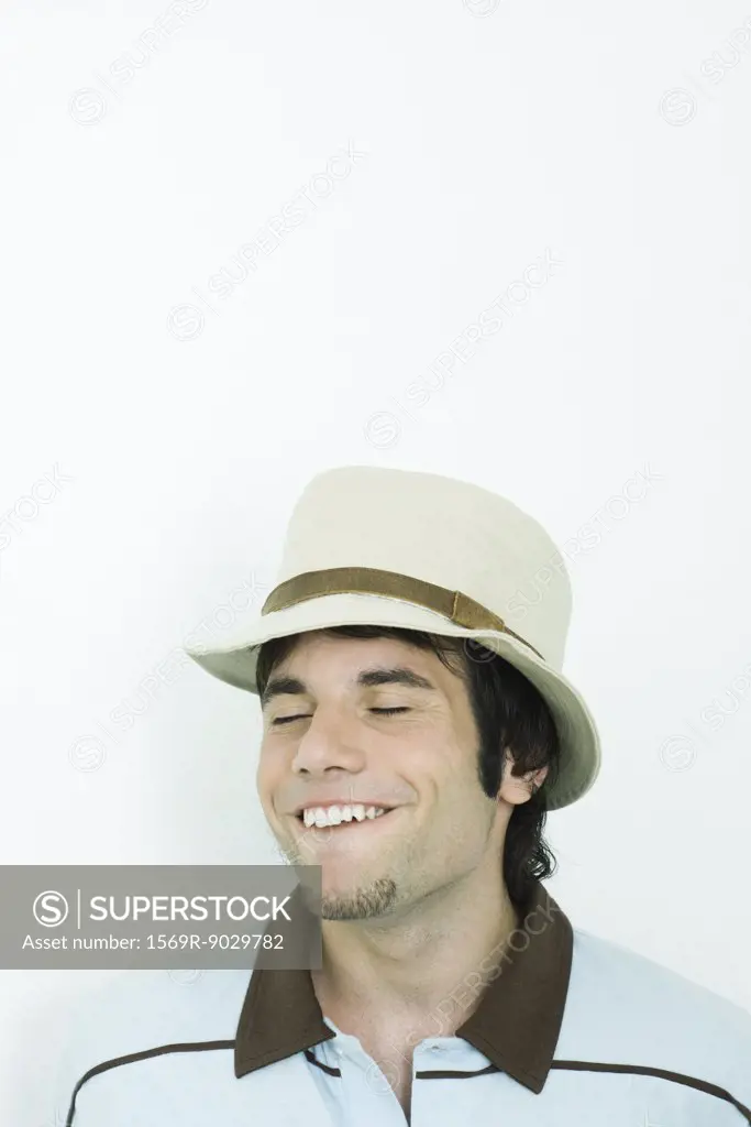 Man wearing hat, making faces, eyes closed