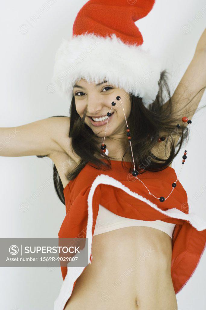 Teenage girl in Santa hat jumping, smiling at camera, midriff exposed -  SuperStock